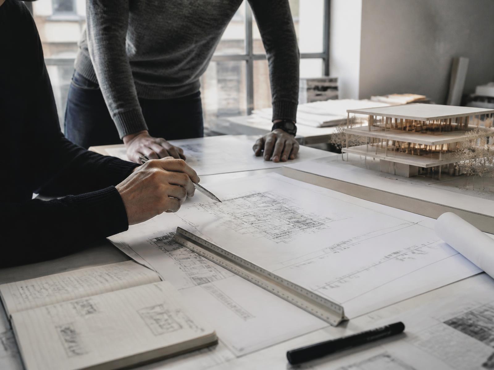 Architects reviewing technical drawings and a physical building model